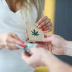 How Purchasing Legal Marijuana Impacts on our Local Economy 1 woman-white-dress-gives-money-receives-bag-marijuana-courier-delivers-order