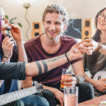 young-woman-preparing-smoke-joint-with-cannabis-while-relaxing-with-friends-home