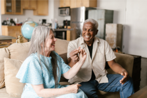 Two seniors laugh and enjoy the health benefits of sharing a cannabis joint in the comfort of their home together